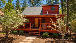 A cabin with a porch, a front door, and a small upper level. - Canyon Cabin (Fawnskin)