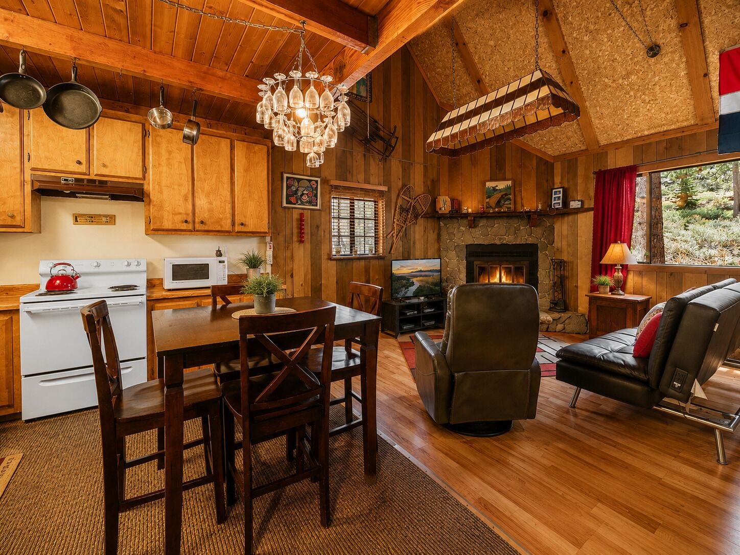 A wooden interior with a dining area, kitchen, fireplace, and seating.