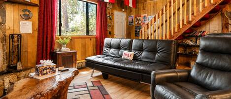 A cozy living room with a leather sofa, a wooden coffee table, and a staircase with wooden railings.
