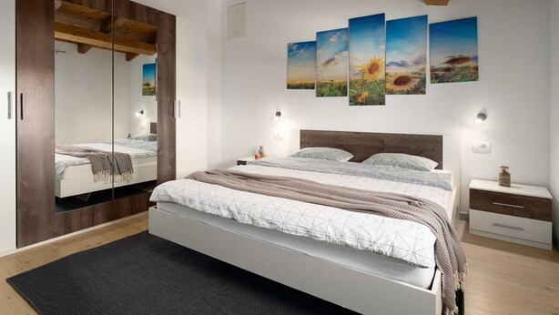 A bedroom with a large bed, a wardrobe, a mirror, a nightstand, and wall art depicting sunflowers. - Villa Vito an peaceful escape near historic town (Labin)