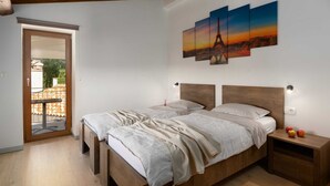 A bedroom with two beds, a wooden ceiling, a balcony door, and a painting of the Eiffel Tower. - Villa Vito an peaceful escape near historic town (Labin)