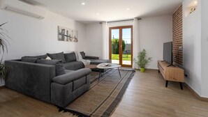 A modern living room with a grey sofa, a coffee table, and a TV on a wooden stand. - Villa Vito an peaceful escape near historic town (Labin)