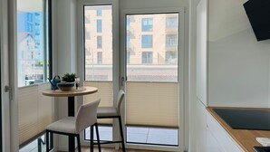 Een klein balkon met een ronde tafel, twee stoelen en een bloempot.