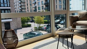 Een moderne woonkamer met grote ramen, een bank, een salontafel en een decoratieve vloerlamp.
