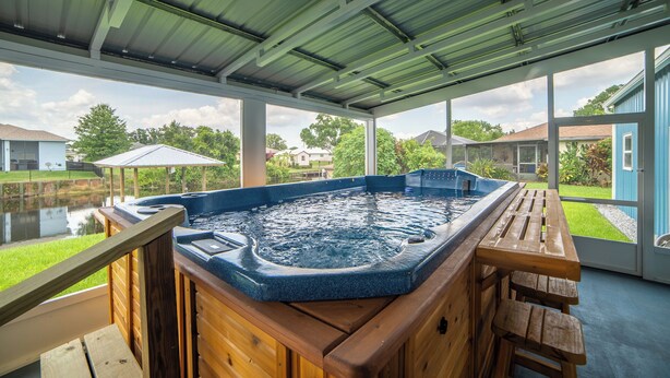 A hot tub under a covered patio with a view of a residential area.