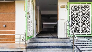 A staircase leading to a room with a green and white decorative door, a metal handrail, and a sign on the wall. - HOTEL GREENLANE SUITES (Hyderabad)