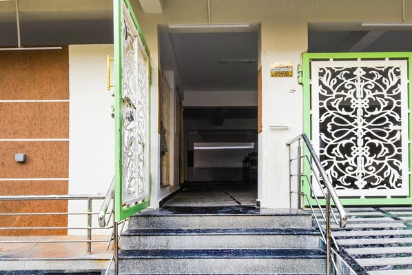 A staircase leading to a room with a green and white decorative door, a metal handrail, and a sign on the wall. - HOTEL GREENLANE SUITES (Hyderabad)