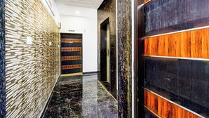 A modern hallway with a patterned wall, a wooden panel wall, and a black marble floor. - HOTEL GREENLANE SUITES (Hyderabad)