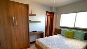 Une chambre dotée d’un grand lit, d’une armoire en bois et d’une fenêtre laissant entrer la lumière naturelle.