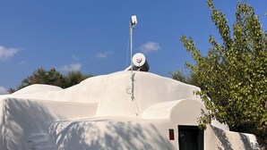 Un bâtiment blanc avec un toit plat, une antenne parabolique et une petite porte.