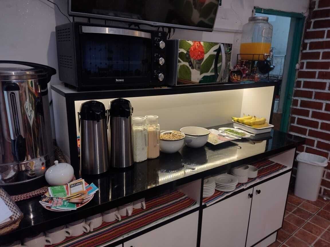Angolo cottura con forno a microonde, macchine da caffè e diversi alimenti sul bancone.