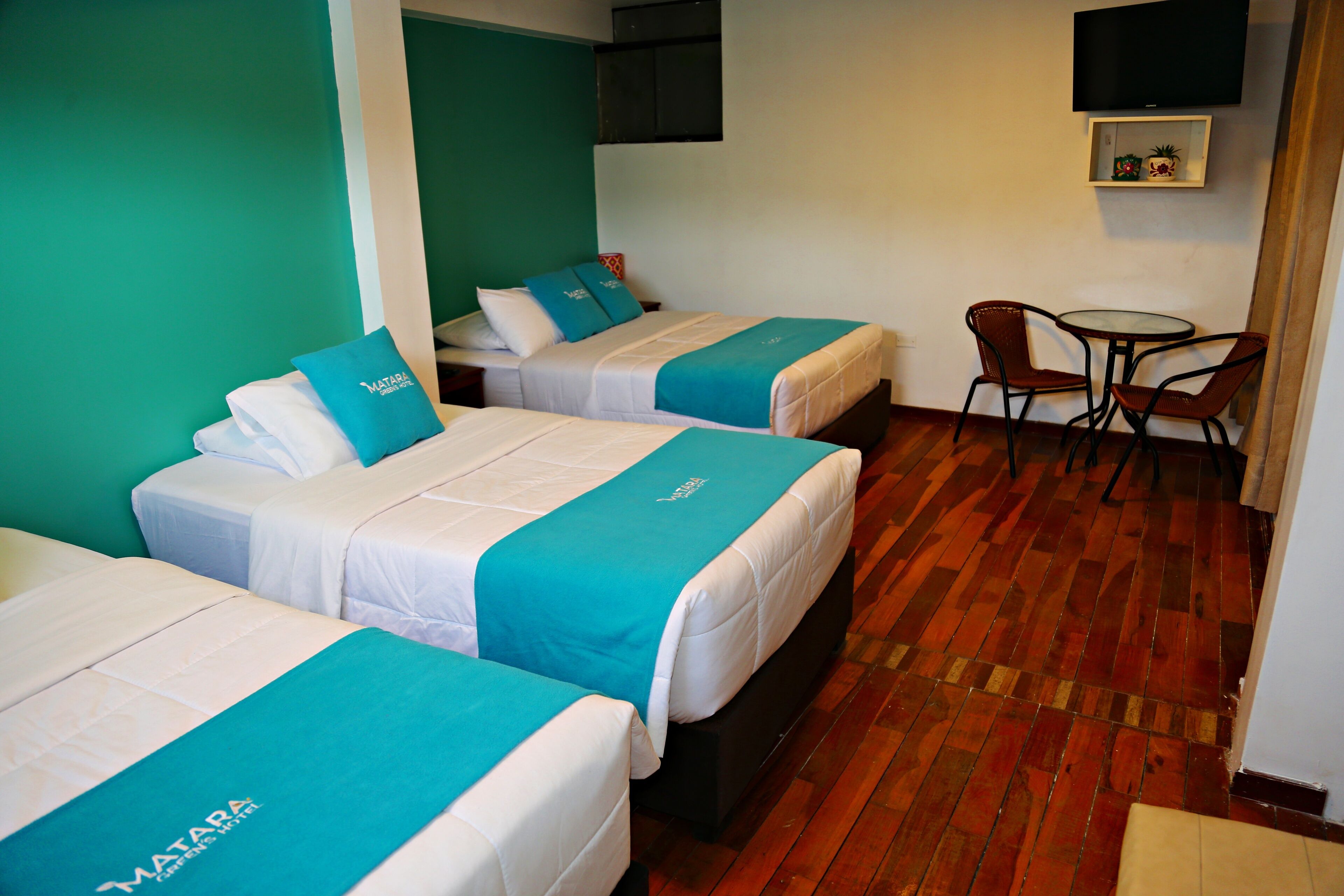 A hotel room with two beds, a small table, and a chair.