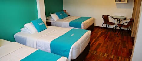 A hotel room with two beds, a small table, and a chair.