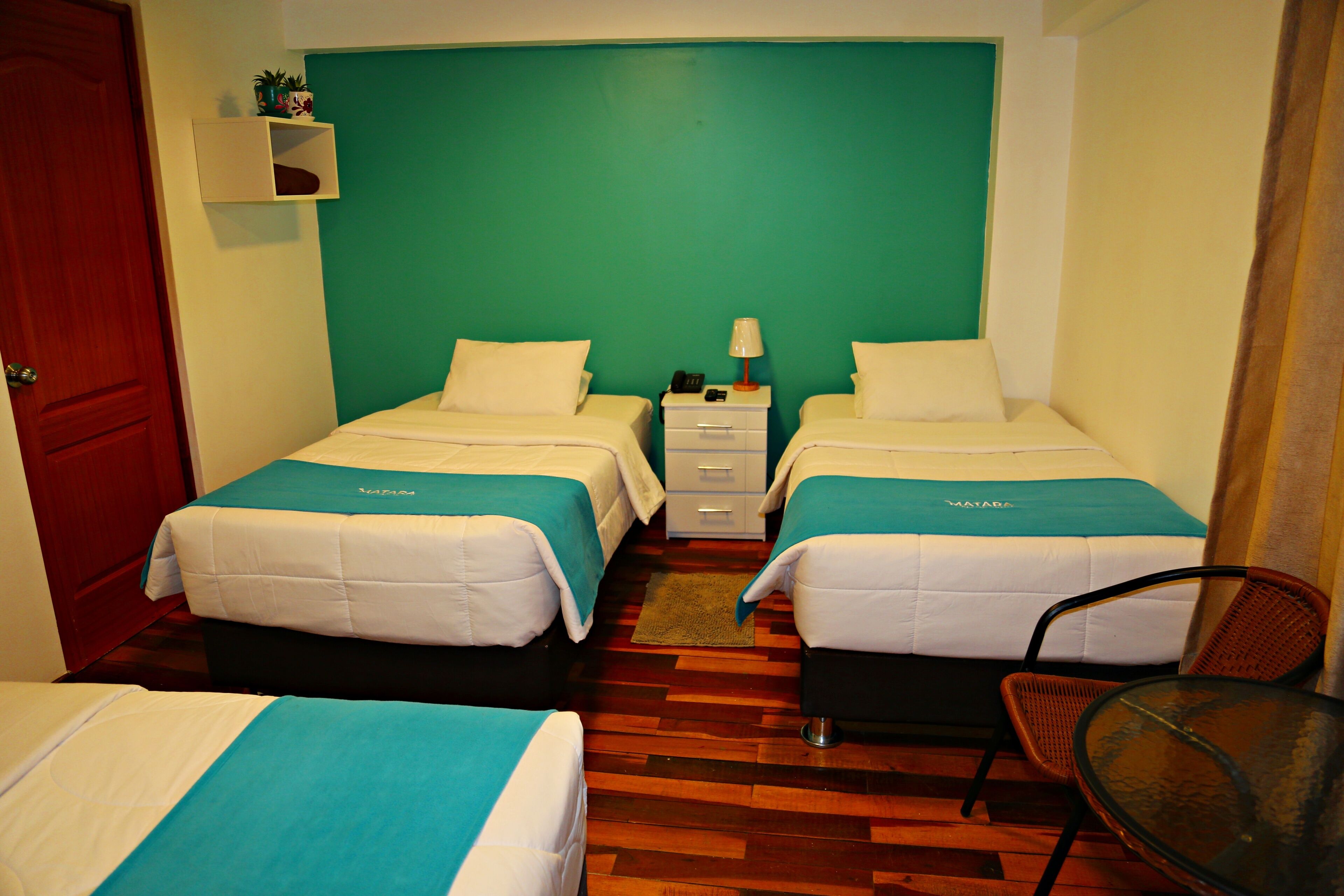 A hotel room with two beds, a small table, and a chair.