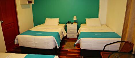 A hotel room with two beds, a small table, and a chair.