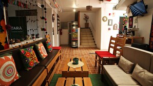 A cozy living area with a sofa, a wooden table, and a bench. There is a staircase leading to another level. - Matara Green's Hotel (Cusco)