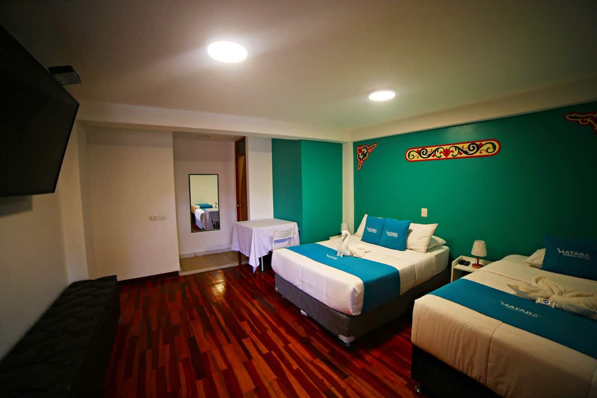 A hotel room with two beds, a small table, and a mirror.
