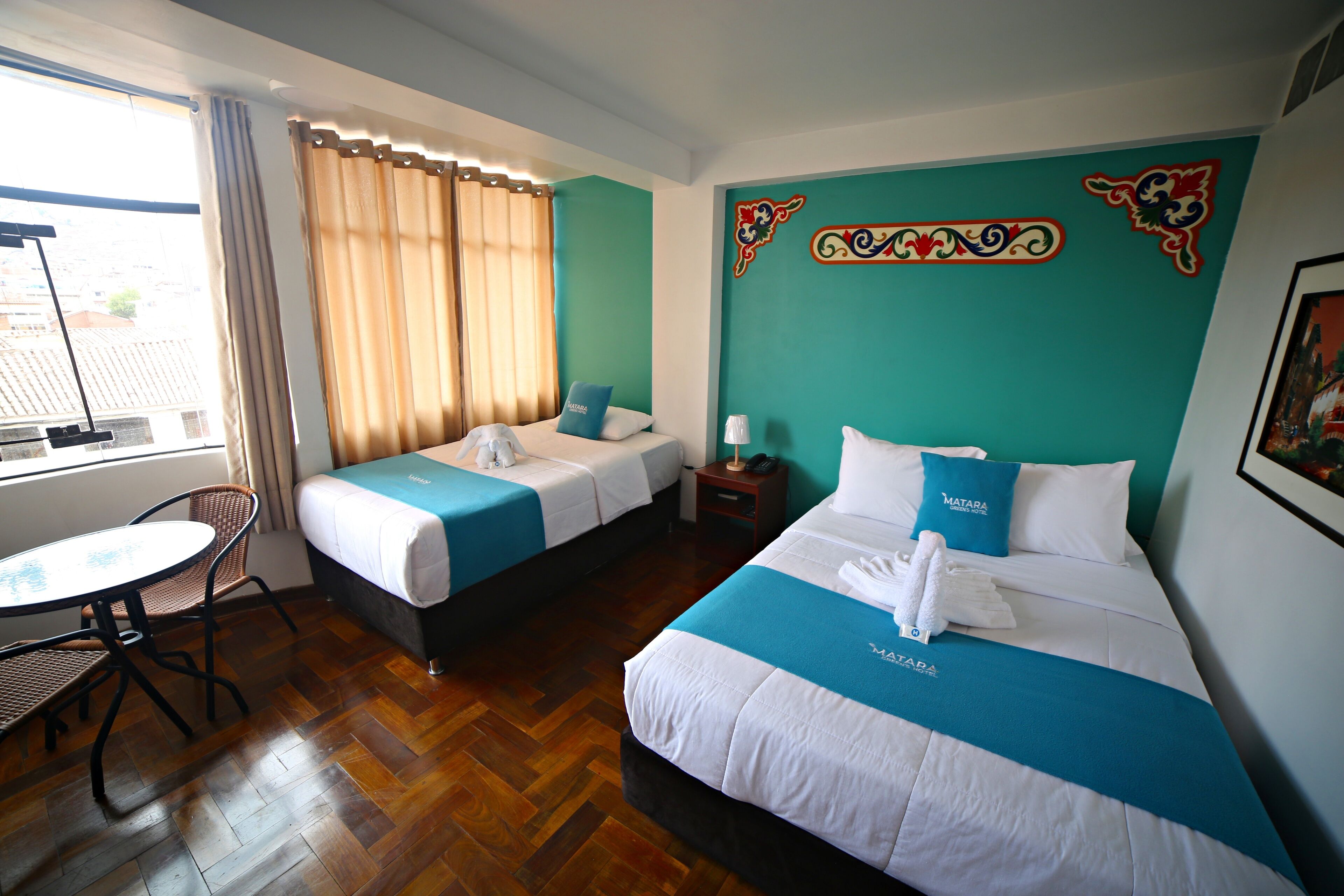 A hotel room with two beds, a small table, and a chair.