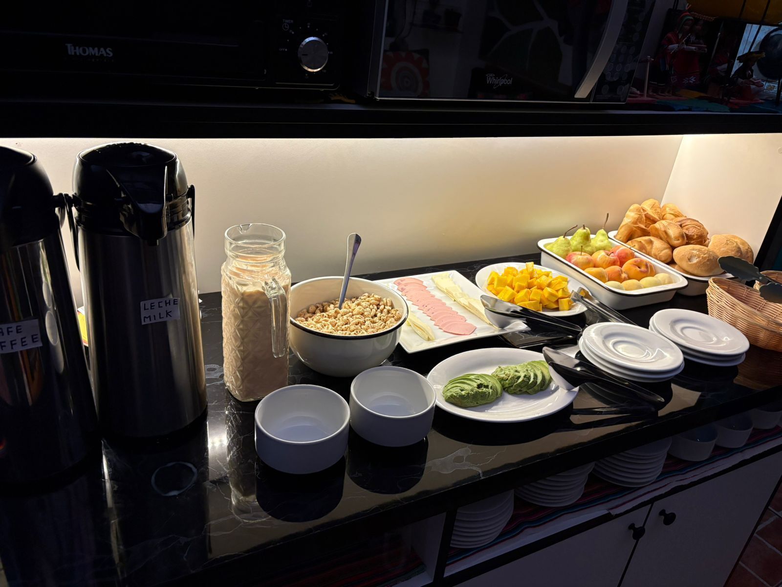 Ein reichhaltiges Buffet mit verschiedenen Speisen und Getränken, darunter Kaffee, Milch, Müsli, Obst und Gebäck.