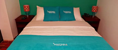 Una habitación de hotel con una cama, dos mesitas de noche y una pared verde.