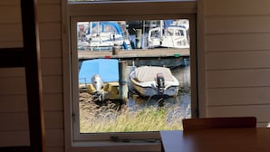 A window with a view of a marina, including boats and a sailboat.