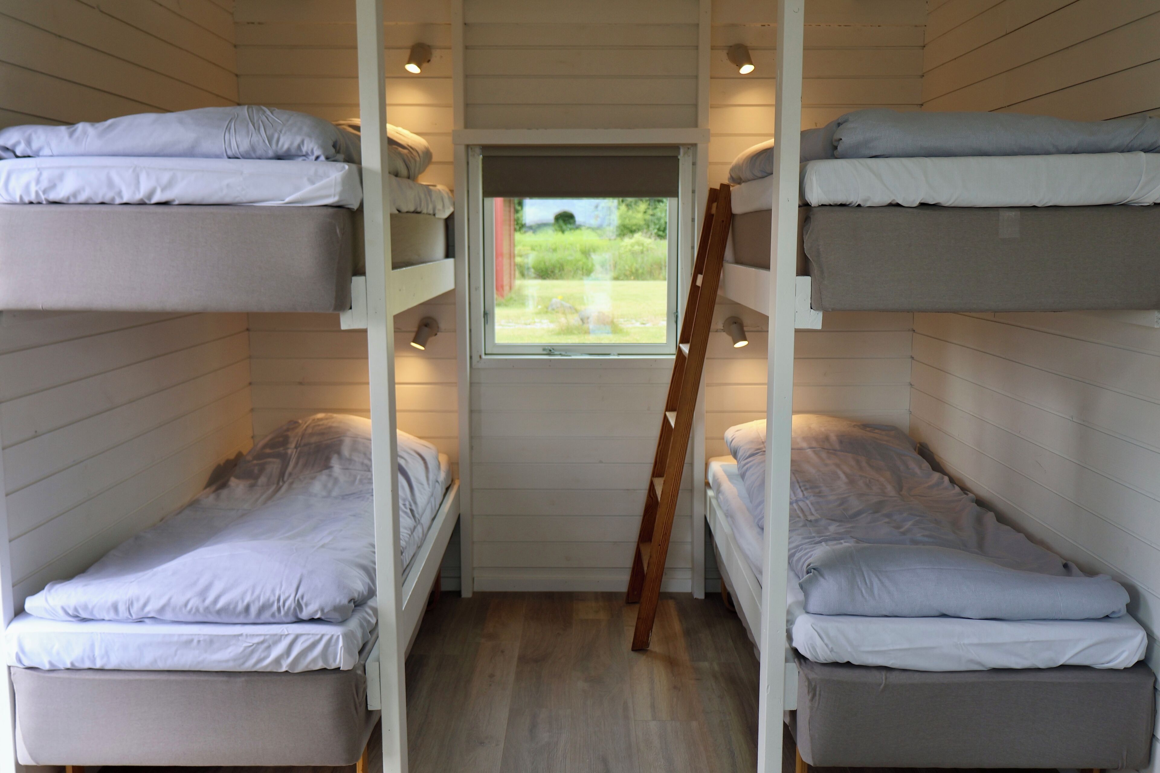 A bunk bed room with a window and a ladder.