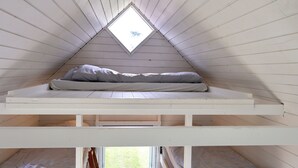 A small attic bedroom with a sloped ceiling and a skylight.