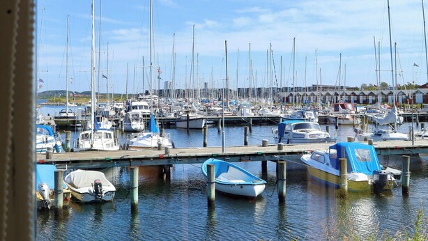 A marina with multiple boats docked at wooden piers.