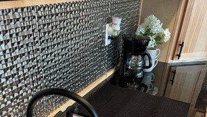 Ein Edelstahl-Spüle mit modernem Wasserhahn, einer strukturierten Spritzschutzeinrichtung und einer Kaffeemaschine auf der Arbeitsfläche.