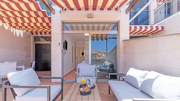 A sunlit outdoor seating area with a table, chairs, and a sofa.