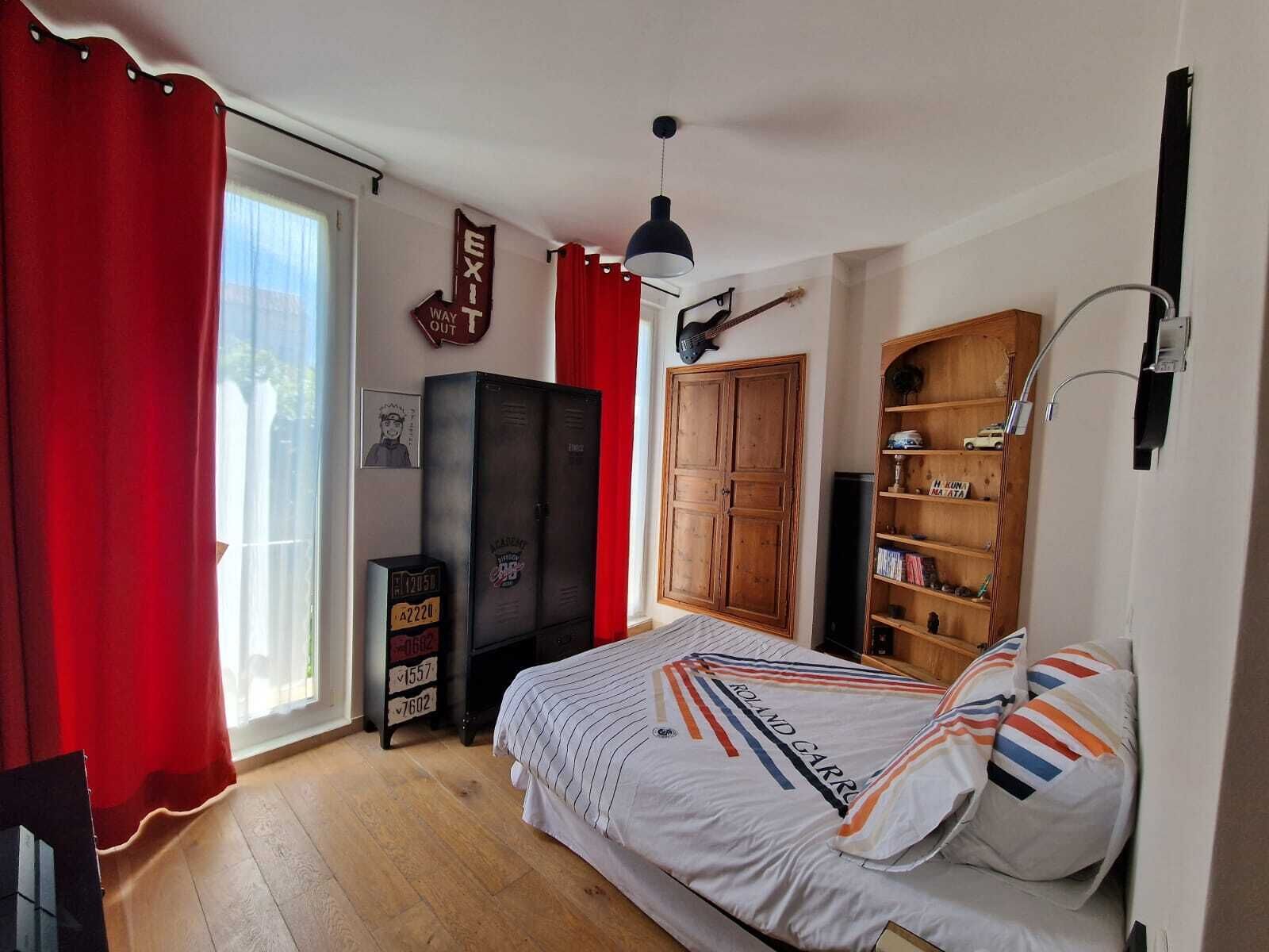 A bedroom with a bed, a wardrobe, a desk, and a bookshelf.