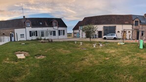 Un quartier résidentiel comprenant deux maisons, une voiture et un petit jardin avec des tondeuses à gazon et des outils de jardinage.