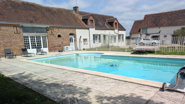 Une piscine rectangulaire, dotée d’une plage carrelée et entourée d’une clôture blanche.