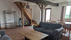 Un salon avec un escalier en bois, un canapé, une table et un coin repas.