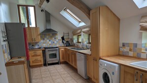 Une cuisine avec des meubles en bois, une cuisinière en acier inoxydable, un lave-vaisselle et un lave-linge.