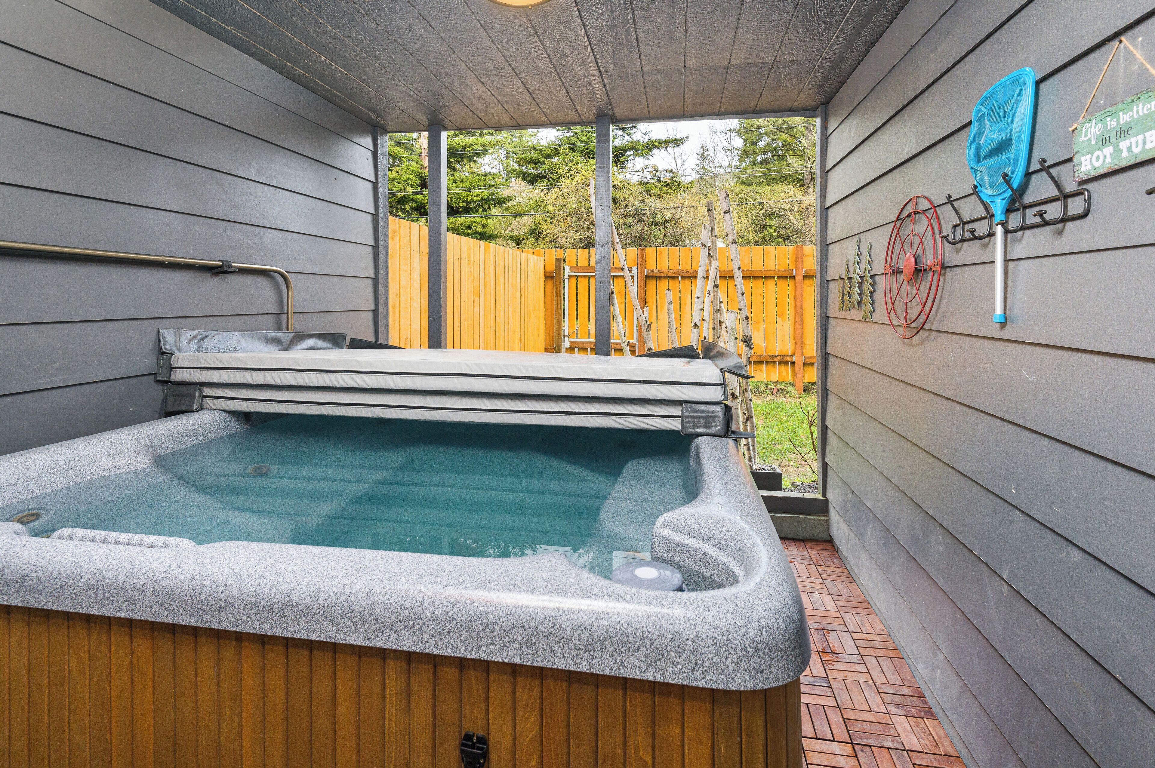 Ein Whirlpool mit einer Holzterrasse und Blick auf einen Holzzaun und Bäume.