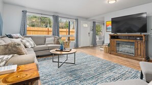 A living room with a sofa, coffee table, TV, and fireplace. - Dog Friendly! Hot Tub~Game Room~Fire Pit~3BR, 2BA~High Speed WIFI~8 Guests Max (Mount Hood Village)