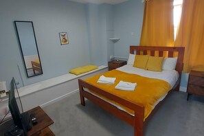 Un dormitorio con cama, mesita de noche, espejo y un cuadro en la pared.