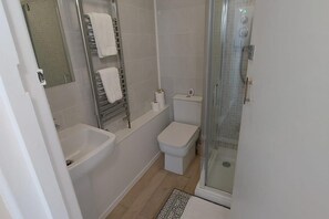A bathroom with a bathtub, toilet, and shower.