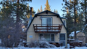 A two-story lodge with a balcony, surrounded by snow-covered trees. - Cardinal Ridge (Big Bear City)
