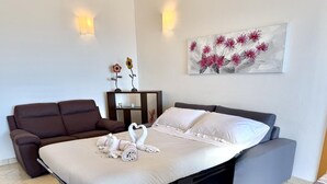 Un dormitorio moderno con cama, sofá y una obra de arte colgada en la pared.