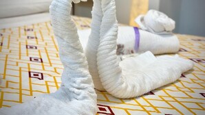 Ein Bett mit einer gemusterten Tagesdecke und zwei in Schwanform gefalteten Bademänteln.