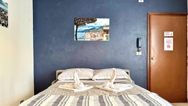 A hotel room with a bed, a framed picture on the wall, and a door with a sign. - Dimora Reti (St. Sampierdarena) genovabb it (GENOVA)