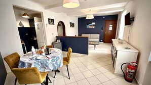 A dining area with a round table, chairs, and a kitchen area with a refrigerator and a sink. - Dimora Reti (St. Sampierdarena) genovabb it (GENOVA)