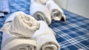 A bed with a blue checkered bedspread and two neatly folded white towels. - Dimora Reti (St. Sampierdarena) genovabb it (GENOVA)