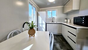 A compact kitchen with white cabinets, a white countertop, a microwave, and a sink.