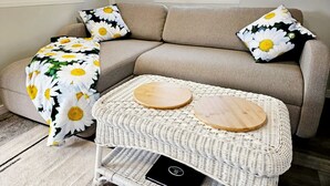 A living room with a sofa, two round wooden side tables, and a woven coffee table.