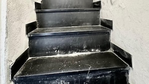 Kapeat, tummat portaat, joiden seinät ovat valkoiset ja joissa on kaiteet molemmilla puolilla.