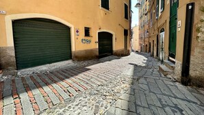 A narrow cobblestone street with buildings on either side, featuring closed shutters and a mix of architectural styles. - Dimora S. M. di Castello (Aquarius) genovabnb it (GENOVA)