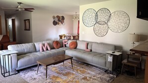 Una sala de estar moderna con un sofá seccional, una mesa de centro y una alfombra estampada.